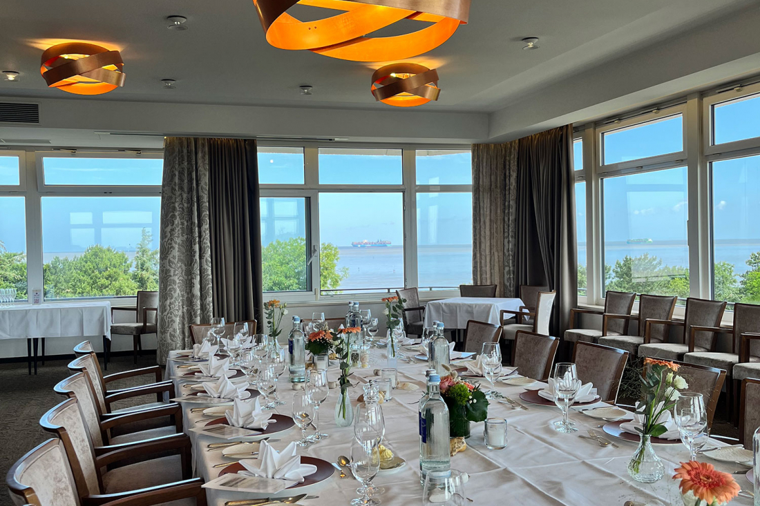 Meeting Room 2 "Sea View" features large windows overlooking the sea, a long dining table with plates, glasses, cutlery, and floral arrangements, as well as modern pendant lights on the ceiling.